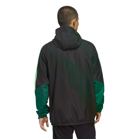 A man seen from behind wearing a black hooded jacket with green paneling on the sleeves, set against a black background.
