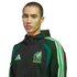A man wearing a black Adidas Mexico national team jacket with bright green accents against a black background.