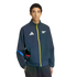 A man wears a navy blue Adidas track jacket with a yellow zipper, featuring a white Adidas logo and the Arsenal FC cannon crest.