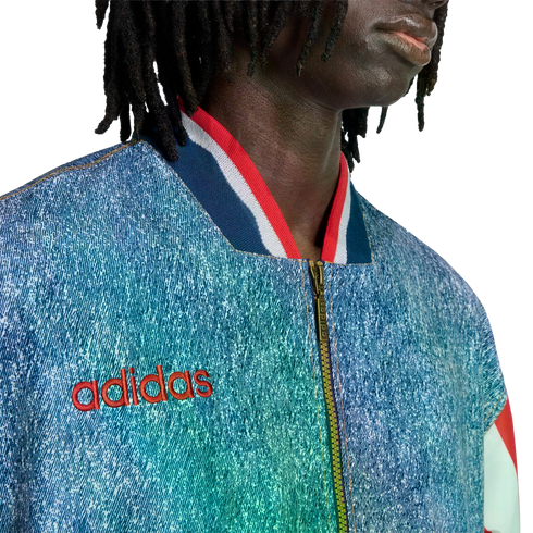 Close-up of a person in a blue denim-textured Adidas jacket with a red logo and striped collar.