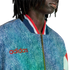 Close-up of a person in a blue denim-textured Adidas jacket with a red logo and striped collar.