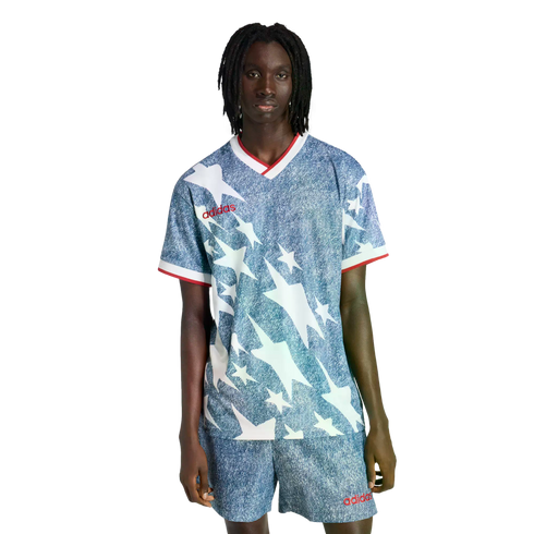 A person wearing a blue denim-textured Adidas soccer kit featuring white stars and red trim, against a black background.