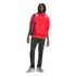 A Black person with dreadlocks stands against a black background in a red hoodie, black track pants, and grey sneakers, with a black crossbody bag.