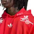 Close-up of a person in a red Adidas x Arsenal hoodie with white embroidered cherub riding a cannon, a Trefoil logo, and "P+AFC" text on the hood.