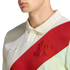 A person wearing a white textured Adidas polo shirt with a red diagonal sash featuring an embroidered red monogram and a white trefoil logo.
