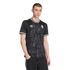 A male model wearing a black floral-patterned Adidas jersey and dark jeans against a solid black background.
