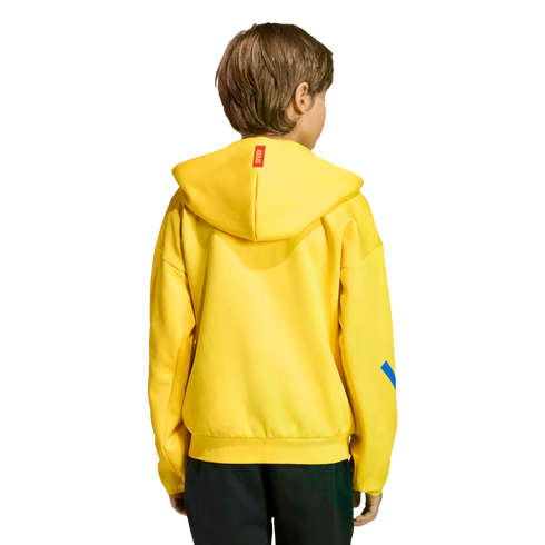 Rear view of a child with light brown hair wearing a bright yellow hoodie and black pants, isolated against a black background.