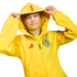 A boy wearing a yellow Adidas Club América hoodie with "ÁGUILAS" on the hood, holding its edges against a black background.