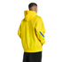 Rear view of a man in a bright yellow hoodie with a red tag and blue sleeve stripe, wearing black pants against a solid black background.