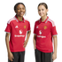 Two children smile in matching red Manchester United football jerseys with the Snapdragon logo against a white background.