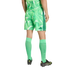Rear view of a person wearing a green geometric-patterned Adidas soccer uniform, bright green calf-high socks, and black Adidas soccer cleats against a black background.