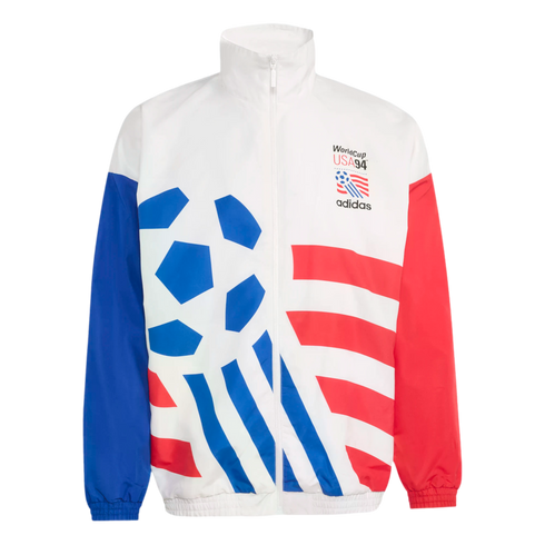 A white Adidas zip-up windbreaker jacket featuring the 1994 World Cup USA logo on the chest. The jacket has a solid blue right sleeve, a solid red left sleeve, and a large graphic design on the front with a blue soccer ball pattern and red horizontal stri