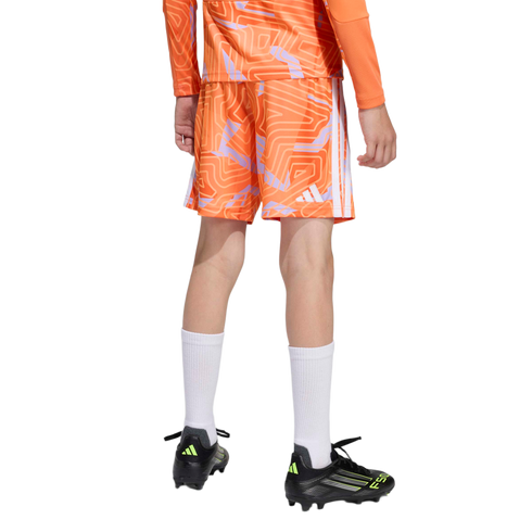 Rear view of a person wearing orange patterned soccer shorts and jersey, high white socks, and black soccer cleats against a plain white background.
