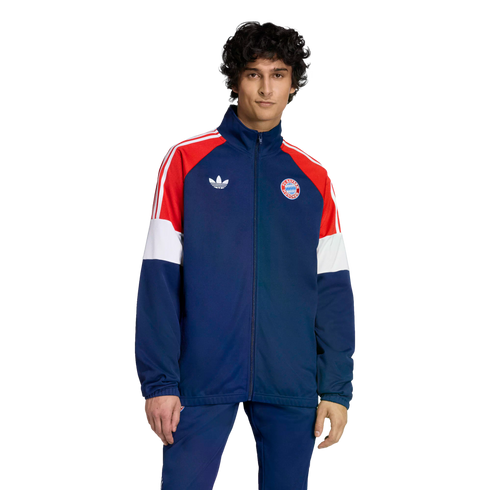 Man in a navy blue, red, and white Adidas Bayern Munich tracksuit featuring the club crest and trefoil logo, against a black background.