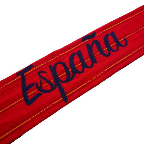 Red fabric band with "España" in navy blue cursive lettering and thin yellow stripes, isolated on black.