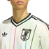 Close-up of a white Adidas Japan jersey with thin vertical rainbow stripes, featuring the Trefoil logo and JFA crest.