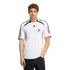 A man models a white Adidas Germany national soccer team jersey and dark jeans against a plain white background.