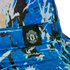 Close-up of a blue and white splash-patterned bucket hat featuring a black label with the white Manchester United crest.