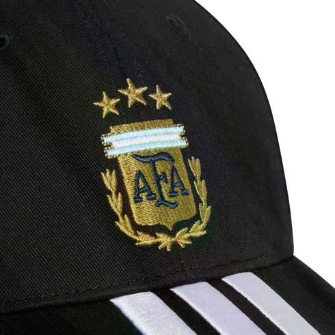 Close-up of a black cap with the gold embroidered Argentina (AFA) crest, three stars above it, and three white stripes on the brim.