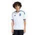 A young person with curly dark hair wearing a white Greece national team soccer jersey with blue accents, standing against a solid black background.