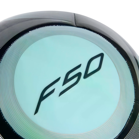 Close-up of a black soccer ball with a light blue circular panel featuring the stylized black "F50" logo.