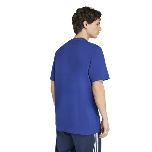 Back view of a man wearing a royal blue crewneck t-shirt and navy blue athletic shorts with white side stripes, against a white background.