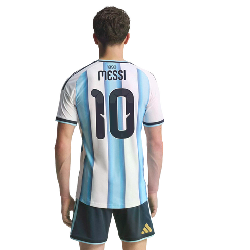 Back view of a man wearing an Argentina soccer jersey with "MESSI" and number 10, paired with dark blue shorts against a solid black background.