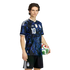 A young man wearing a black and blue patterned Argentina soccer kit with the number 10, holding a soccer ball against a black background.