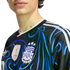 Close-up of a person wearing a black and blue patterned Argentina football jersey, featuring the AFA crest with three stars and the FIFA World Champions 2022 gold patch.