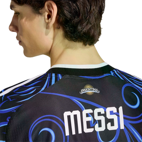 Back view of a person wearing a black Argentina soccer jersey with blue swirl patterns and "MESSI" printed in bold white letters.