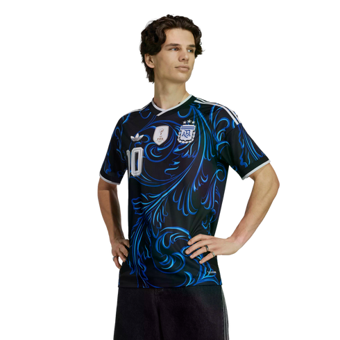 Man wearing a black Argentina football jersey with blue swirling patterns and the number 10, standing with hands on hips against a black background.