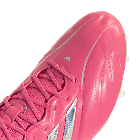 A close-up shot of a bright pink Adidas soccer cleat against a white background, showcasing the laces and textured upper material.