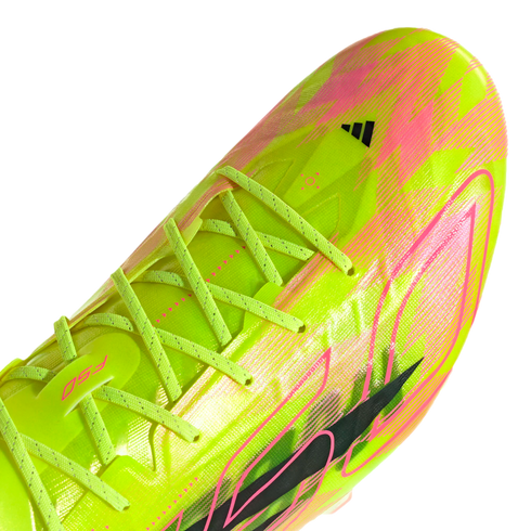 Close-up of a neon yellow and pink Adidas F50 football boot with crossed lime laces, set against a black background. Bold graphic patterns decorate the upper.