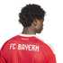Back view of a person with dark curly hair wearing a red striped FC Bayern soccer jersey with white "FC BAYERN" and "MIA SAN MIA" lettering.