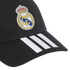 A black baseball cap featuring the Real Madrid club crest on the crown and three white Adidas stripes on the visor.