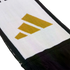 Close-up of a white knitted scarf with a black border, featuring a gold three-stripe logo and black fringes at the end.