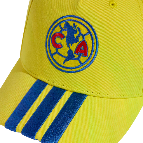 Close-up of a yellow baseball cap with the Club América logo embroidered on the front and three blue stripes on the brim.