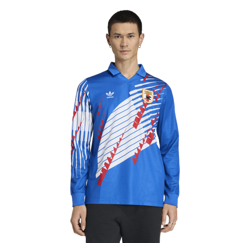 A male model wearing a long-sleeved blue Adidas soccer jersey with white stripes, red graphic accents, and a team crest.