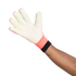 A person's arm and hand wearing a white goalkeeper glove with a coral and black wrist cuff, fingers spread open against a white background.