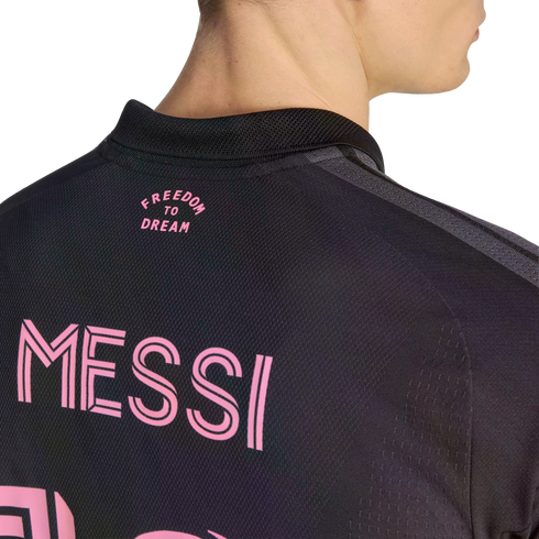 A close-up view from behind a person wearing a black jersey with pink lettering that reads "MESSI" across the back and "FREEDOM TO DREAM" near the collar.