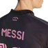 A close-up view from behind a person wearing a black jersey with pink lettering that reads "MESSI" across the back and "FREEDOM TO DREAM" near the collar.