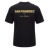 Back of a black t-shirt with "SAN FRANCISCO" in bold gold lettering across the upper back and smaller gold branding logos centered underneath.