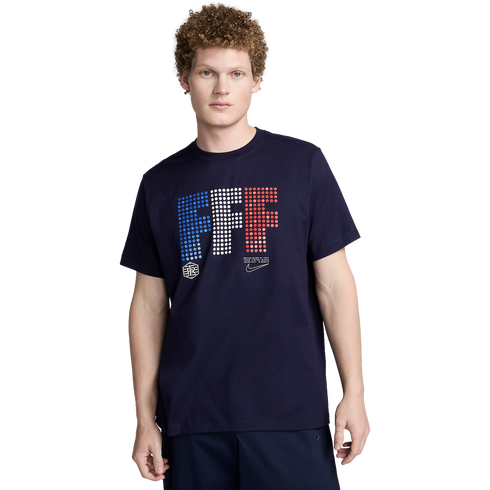 A man with curly hair wearing a navy blue Nike France t-shirt with a dotted "FFF" graphic in blue, white, and red.