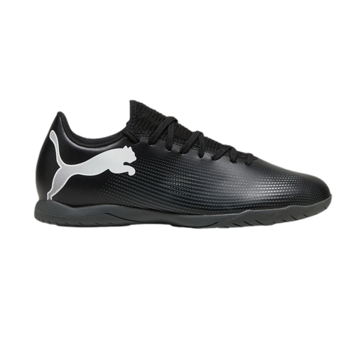Profile view of a black Puma indoor soccer shoe with a large white logo on the side and a flat rubber sole.