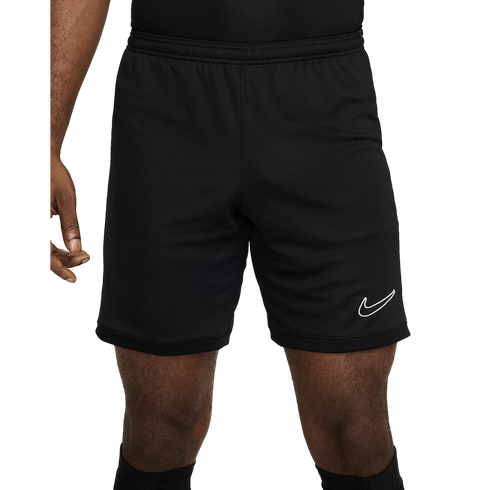 A person wearing black Nike athletic shorts featuring a white swoosh logo on the left leg and a textured mesh hem.