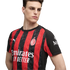 A young man models the red and black striped AC Milan home jersey, featuring the club crest and sponsor logos.
