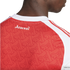 Close-up of the back of a red Arsenal jersey with white gothic-style text reading "Arsenal" and a repeating "A" monogram pattern across the fabric.
