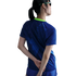 Rear view of a person wearing a blue patterned athletic shirt with a lime green collar and matching sunglasses, hands behind their back against a white background.