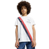 A boy with an afro wears a white Manchester City soccer jersey with a red and navy diagonal stripe, paired with blue jeans, against a plain white background.