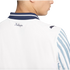 Close-up back view of a white Puma x KidSuper shirt with a navy striped collar, "KidSuper" script logo, and a Puma logo on the shoulder.